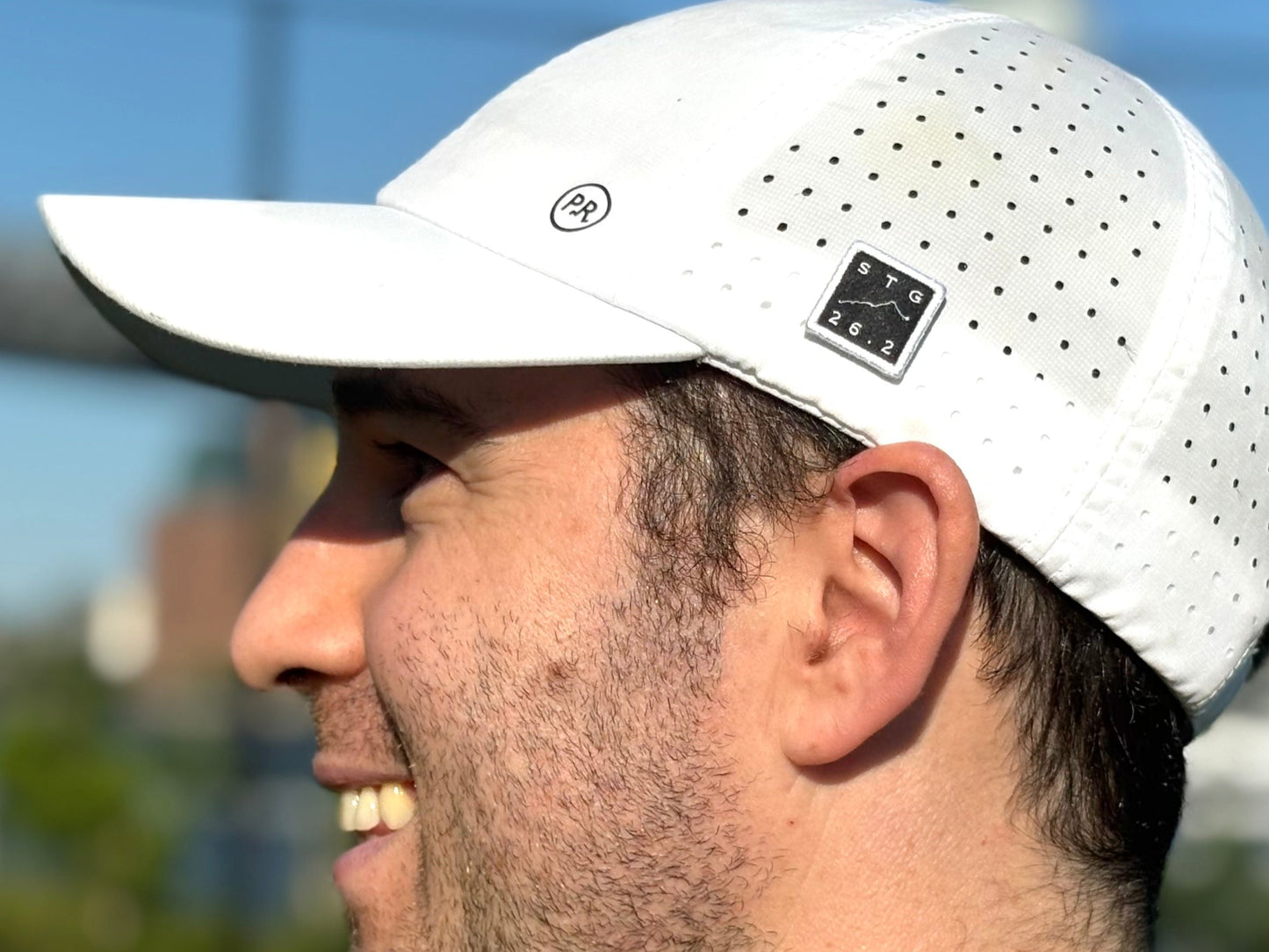 Man wearing a white cap with a blurred outdoor background St. George Marathon Hat